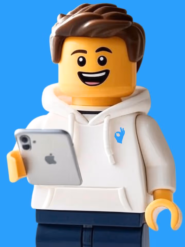 LEGO minifigure with brown hair wearing a white hoodie holding a silver iPhone, smiling with a blue background.